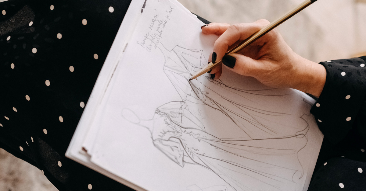 A fashion designer sketching a bridal dress with a pencil. She creates the front and back sides of the gown.