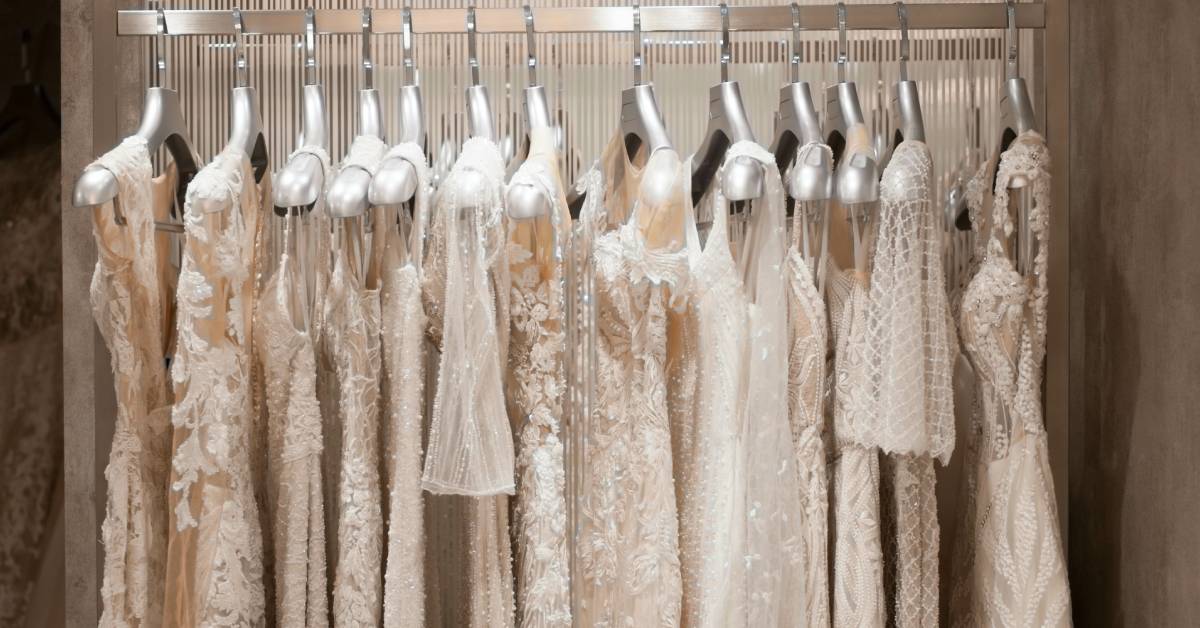 A rack full of elegant dresses in a wedding salon. They all have slight differences in their patterns and fabrics.